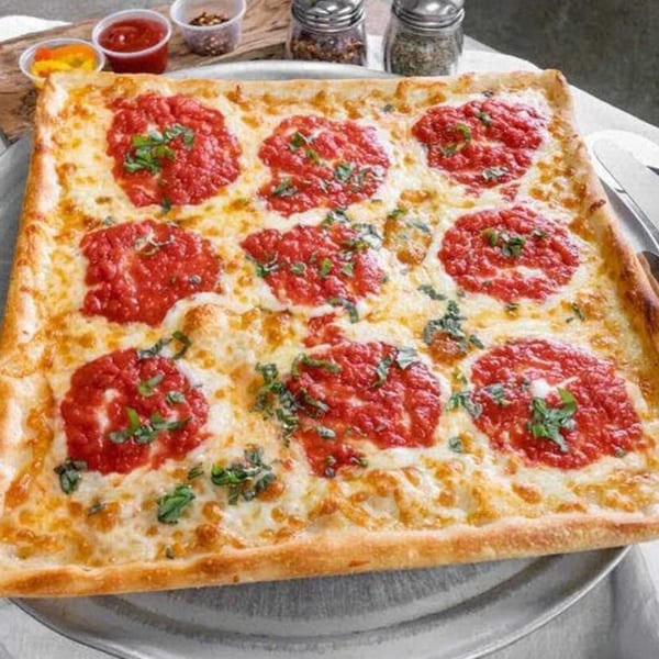 A square Enzo's Pizzeria pizza with dollops of red sauce, melted cheese, and fresh basil.