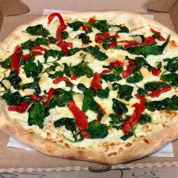 Enzo's Pizzeria white pizza with spinach, roasted red peppers, and garlic in a box.