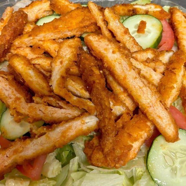 Crispy fried chicken strips, sliced cucumbers, and tomatoes on a bed of lettuce.