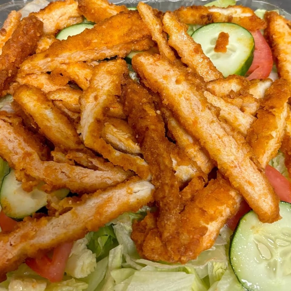 Crispy fried chicken strips, sliced cucumbers, and tomatoes on a bed of lettuce.